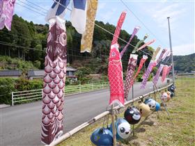 道沿いに設置されたイラスト付き漁業用ブイ（浮き）と小さなこいのぼり